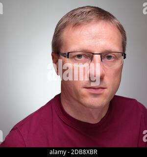 Potrait of a man with glasses and sceptical glimpse grey background Stock Photo