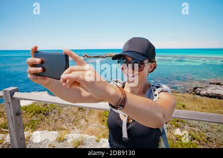 Woman uses her phone to capture a selfie while on vacation on Rottnest Island, Australia. Stock Photo