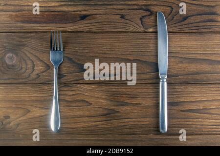 Fork and knife on a dark wooden table. Top views with clear space. Stock Photo