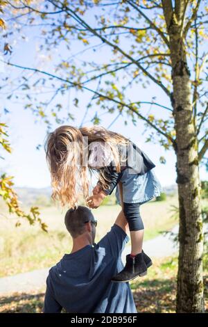 Father playfully lifts his daughter high above his head. Stock Photo