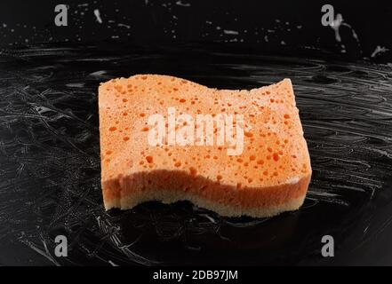 rectangular wet orange washcloth with white foam on a black background, top view Stock Photo