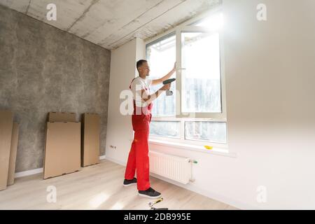master with a screwdriver sets fittings on the window Stock Photo