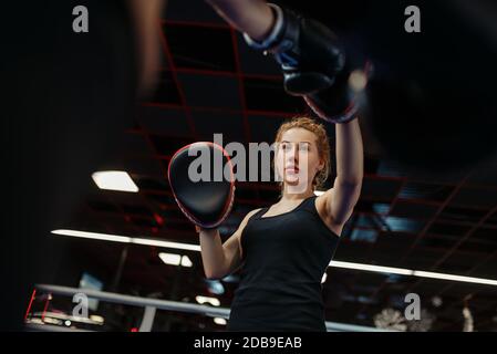 Two women in gloves boxing on the ring, box workout. Female boxers in gym, kickboxing sparring partners in sport club, punches practice Stock Photo