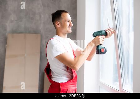 master with a screwdriver sets fittings on the window Stock Photo