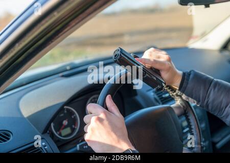 hands with gun on steering wheel of passenger car. Stock Photo