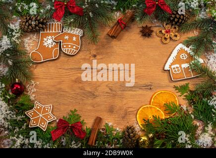 Christmas and New Year decorations with elements of gingerbread cookies, Christmas tree branches, cones, dried oranges, cinnamon and snow on a wooden Stock Photo