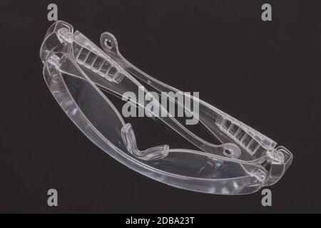 Coronavirus protective measures. Closeup of a clear transparent safety glasses on a dark background. Eye protection for infection as part of personal Stock Photo