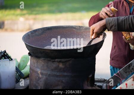 Islamabad, Islamabad Capital Territory, Pakistan - February 2, 2020,  A Young boy is roasting fresh corn for the customers. Stock Photo