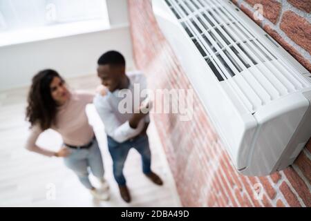 Portrait Of Happy Couple Holding Remote Control Air Conditioner Stock Photo
