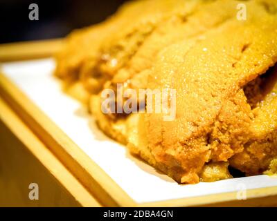 Closeup Fresh Uni. Atlantic sea urchin meat in wooden tray Stock Photo