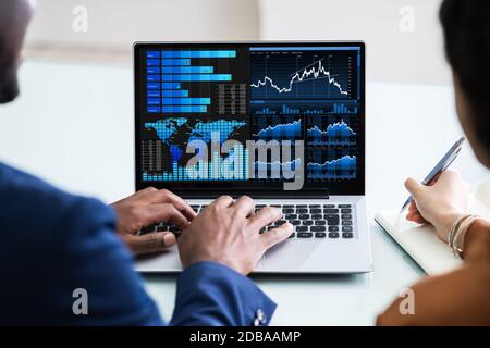 Two Businesspeople Analyzing Financial Graph On Laptop Stock Photo