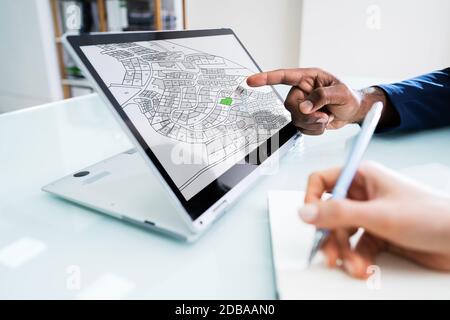 Close-up Of A Businesspeople Analyzing Cadastre Map On Computer In The Office Stock Photo
