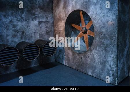 Industrial interior of an old factory with pipes, ventilation grills and a large propeller with blades. Stock Photo