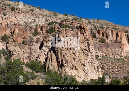 Large rock cliffs inside of Frijoles Canyon that was home to the ancestral Pueblo people who carved cave dwellings at the base in Bandelier National M Stock Photo