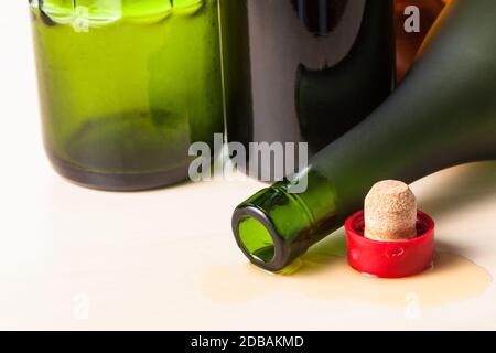 overturned brandy bottle and cork closeup near empty bottles on wooden board Stock Photo