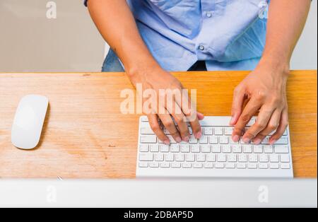 Top view overhead flat lay of Asian businessman working write keyboard computer on desk home office under curfew quarantine pandemic coronavirus COVID Stock Photo