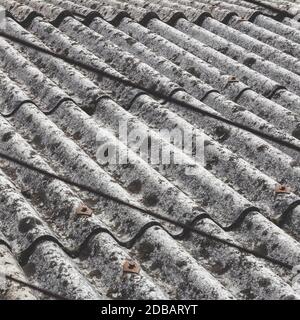 Old and dangerous asbestos roof, one of the most dangerous materials in the construction industry. Eternit roof covering of a scruffy old and moldy. Stock Photo