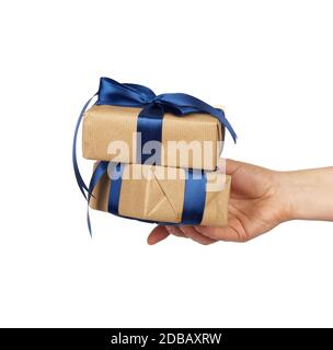 hand holds a stack of wrapped gifts in brown craft paper with tied silk bows, subject is isolated on a white background Stock Photo