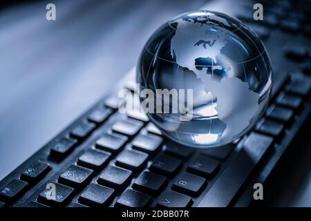 Glass globe on computer keyboard Stock Photo