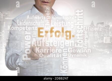 Erfolg Wordcloud (in german success) touchscreen is operated by man. Stock Photo