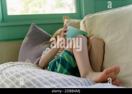 Boy (4-5) using smartphone on sofa Stock Photo