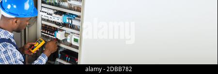 African Electrician Checking And Testing Fuse Box Stock Photo