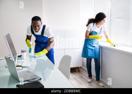 Young Male And Female Cleaners Cleaning Office Stock Photo