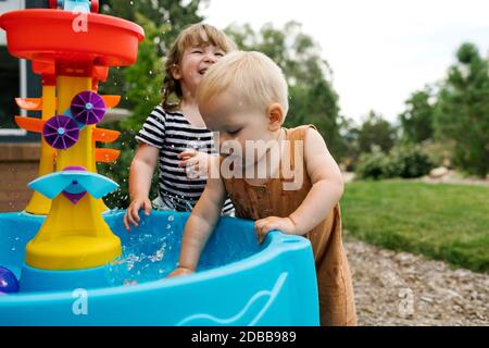 Toddler girl (2-3) and baby boy (18-23 months) playing in garden Stock Photo