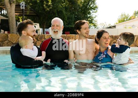 Multigeneration family with kids ( 2-3, 6-11 months) standing in outdoors swimming pool Stock Photo