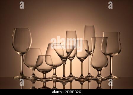 Set of glasses for different alcoholic drinks and cocktails on dark brown background. Empty clear glassware. Stock Photo