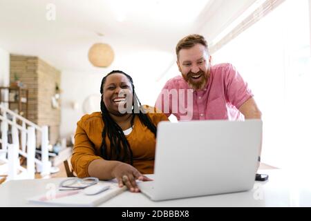 Man and woman looking at laptop at desk in home office Stock Photo