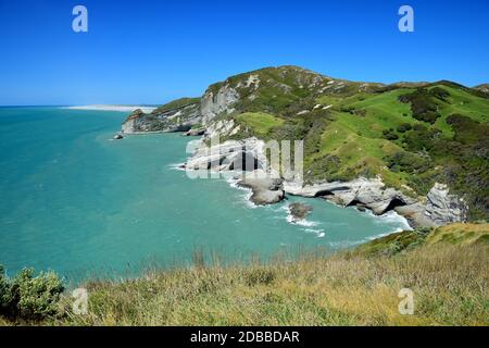 Beautiful New Zealand landscape near Cape Farewell with rocks, hills and ocean. Farewell Spit in the background. South Island. Stock Photo