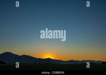 USA, Idaho, Bellevue, Sun setting behind hills Stock Photo