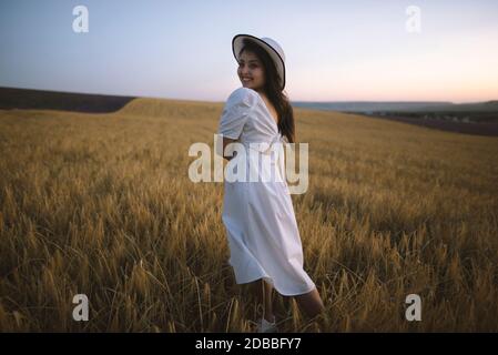 France, Young woman in white dress standing in cereal field Stock Photo