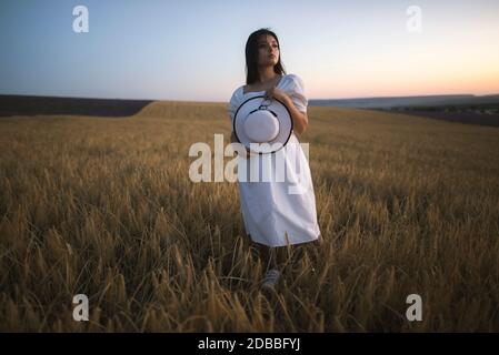 France, Young woman in white dress standing in cereal field Stock Photo