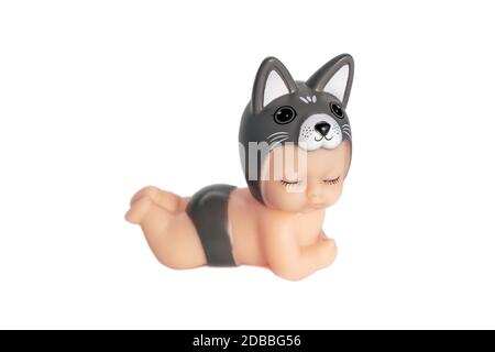 Cute little doll in a dog costume with closed eyes. Lies on a white isolated background. An adorable toy for a gift or a child's play. Soft focus. Stock Photo