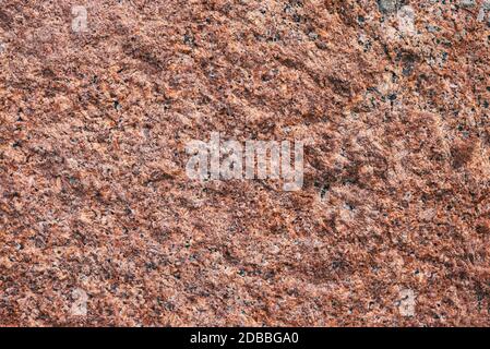 Background granite is a red stone with small black and white spots on the entire surface. Texture for an inscription, text, or logo. Stock Photo
