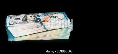 Isolated bundle of dollars. A large stack of hundred-dollar bills lies on a black background in the center of the image with a reflection. A color ful Stock Photo