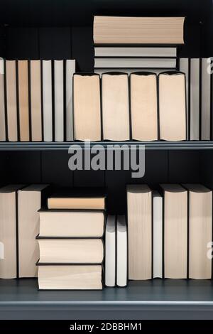 Bookshelf with series of books in piles and rows Stock Photo