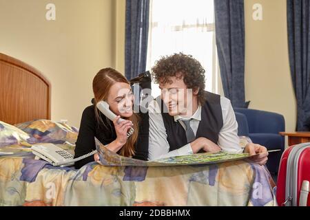 Happy young family with map lays on the bed. Vacation. Stock Photo