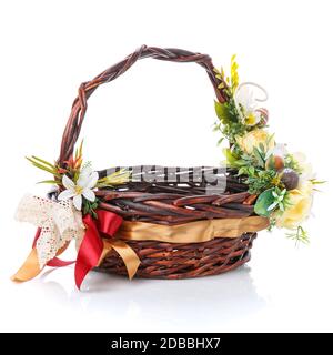 Wicker Easter basket decorated with yellow flowers and decorative colored eggs on white background Stock Photo