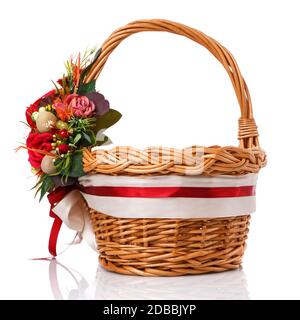 Brown wicker basket with original handle. Decor with flowers, eggs and ribbons. Made for Easter celebration. Isolated on a white background Stock Photo