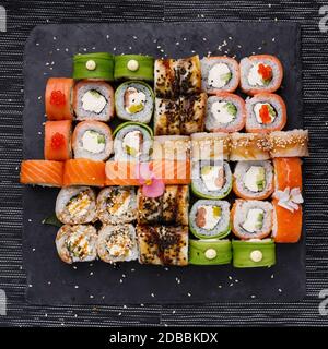 Japanese sushi set. Various types of roles on plate over stone background. Top view, flat lay. Stock Photo