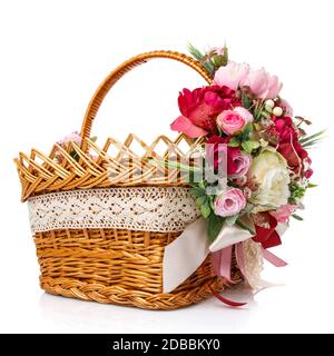 Original square wicker basket with Easter floral arrangements. Great scenery with pink peonies and greenery. Ribbons and lace. Isolated on white backg Stock Photo