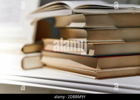 Book shelf with books in piles and rows Stock Photo
