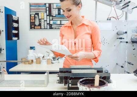 Experienced worker checking design or a print to be run on printing machine Stock Photo
