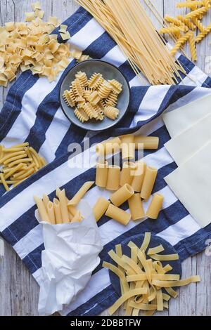 a mix of many different egg noodles and pasta on blue white and wooden background Stock Photo