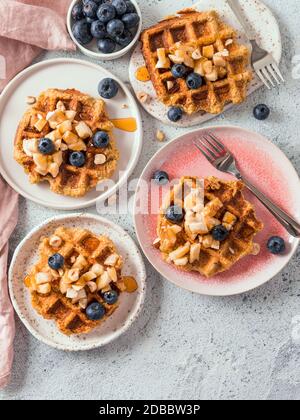 Easy healthy gluten free oat waffles with copy space. Plates with appetizing homemade waffles with oat flour decorated blueberries, bananas and honey Stock Photo