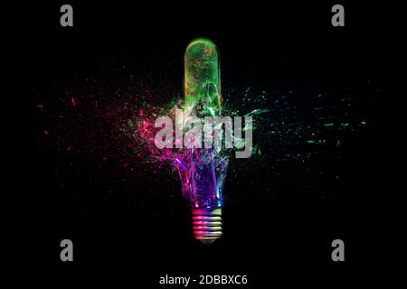 high speed image of a real explosion of an industrial light bulb, colored lights and dark background. concept of strength and fragility. creativity an Stock Photo