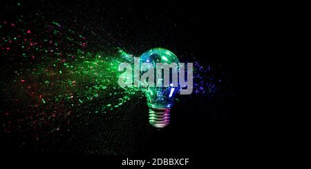 high speed image of a real explosion of a traditional tungsten light bulb. black background, colored lights. concept of fragility, crisis and obsolete Stock Photo